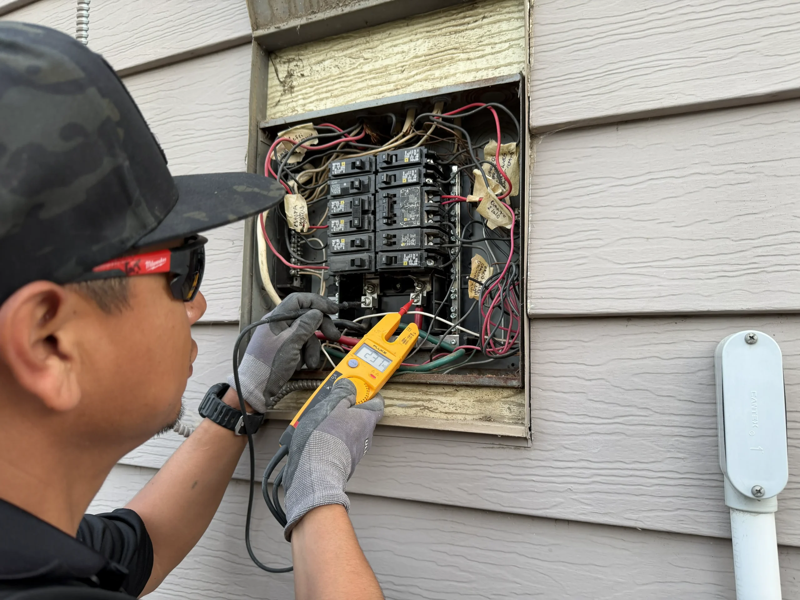 Certified residential electrician inspecting home wiring and breaker box.